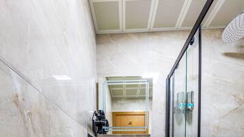 Un baño con piso de mármol, cabina de ducha de vidrio y tocador con espejo.
