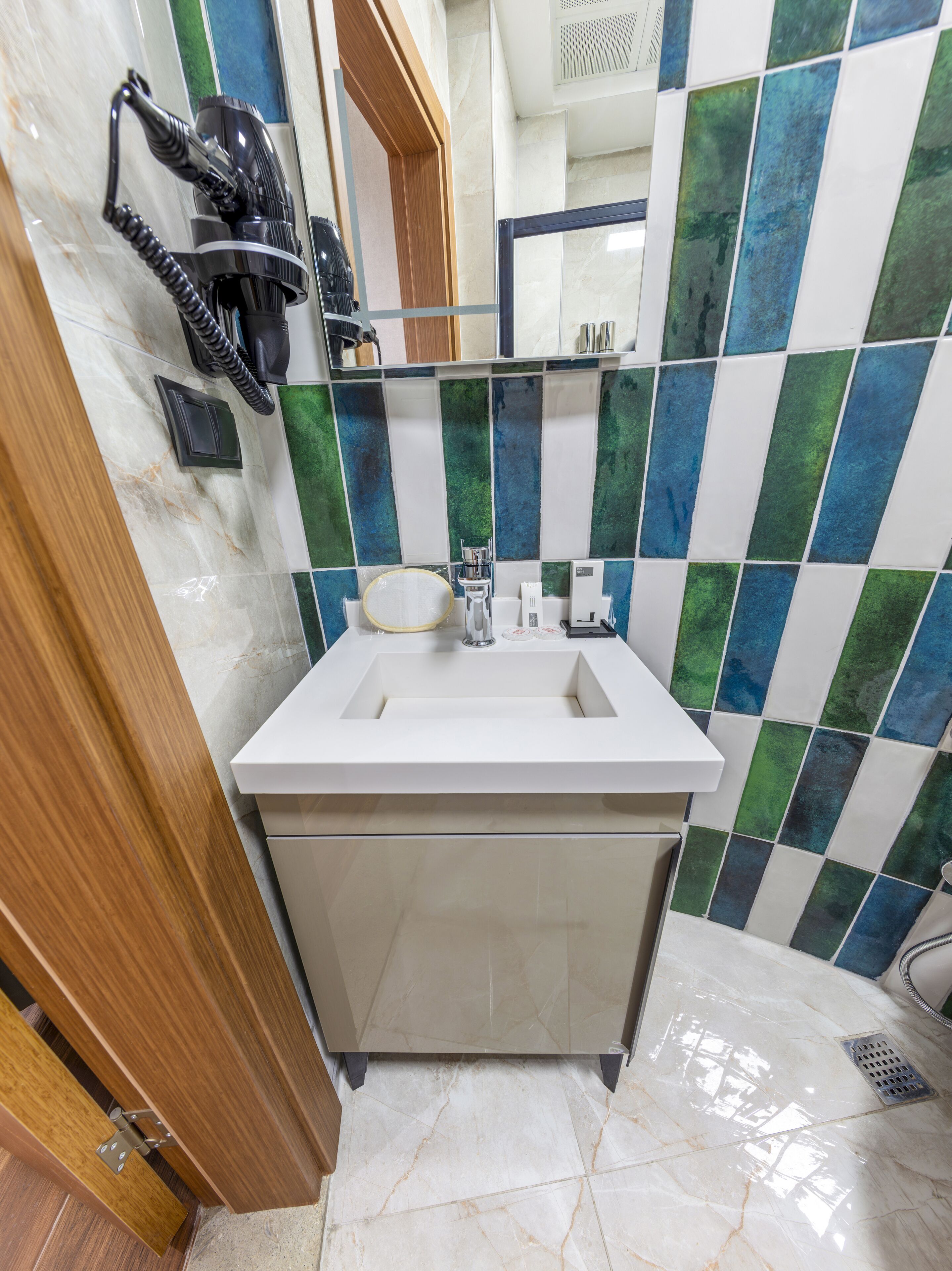 A bathroom with a white sink, a mirror, and a hairdryer mounted on the wall.