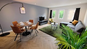 A modern living room with a dining area, a sofa, and a TV.