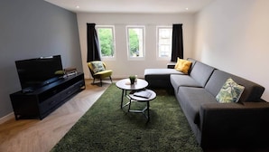 A modern living room with a flat-screen TV, a sofa, a chair, and a coffee table.