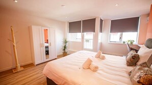 Un dormitorio con cama, armario, ventana y una planta.