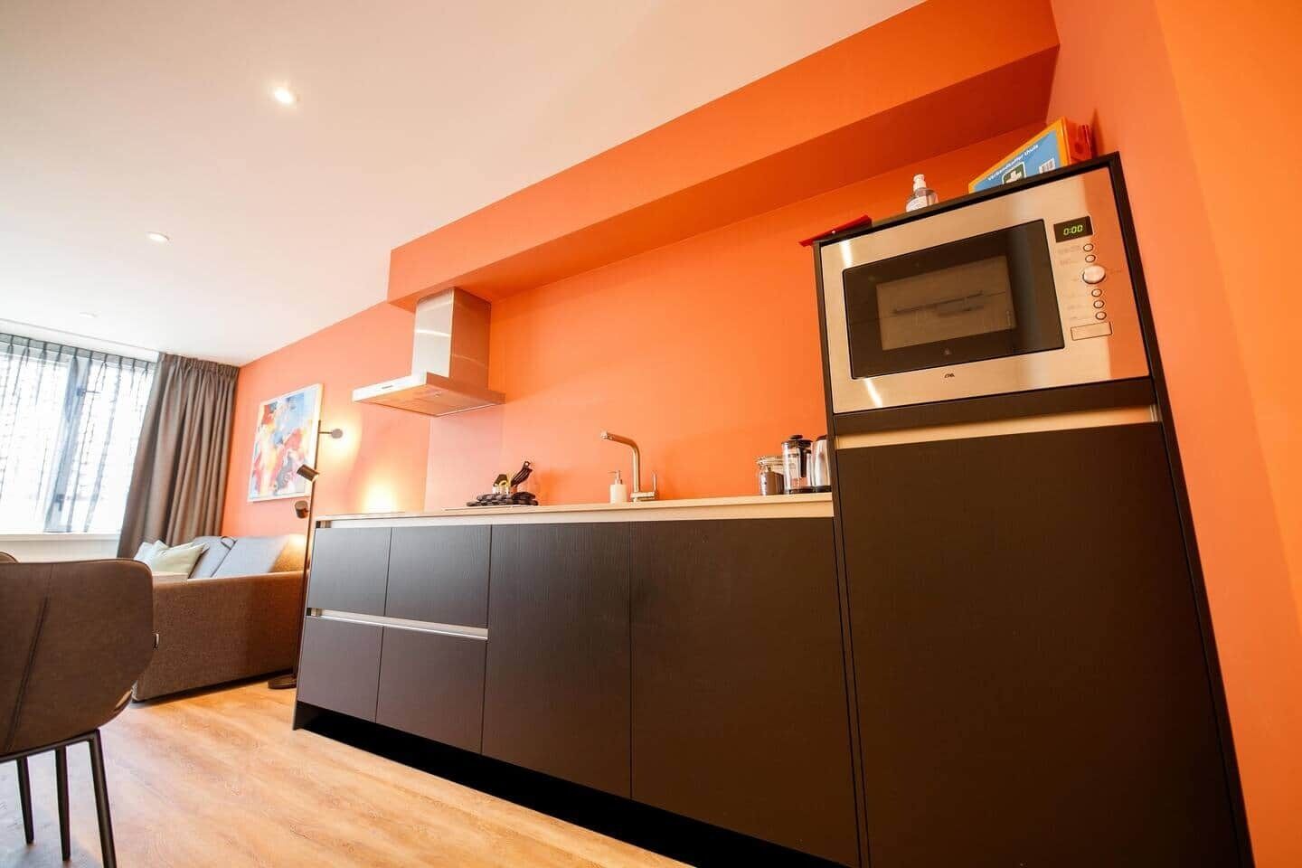 A modern kitchen with a built-in microwave, oven, and sink. There is a dining area with a table and chairs.
