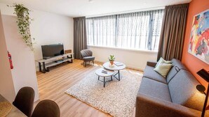Una sala moderna con sofá, mesa de centro, televisor y planta en maceta.