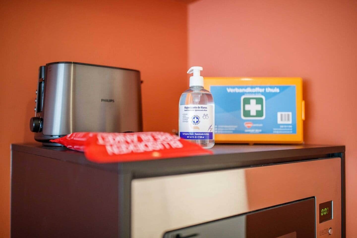 A minibar with a Philips coffee maker, a bottle of hand sanitizer, and a box of Verandahther Plus.