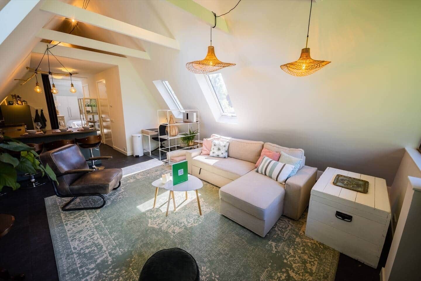 Un appartement de style « loft » avec de hauts plafonds, un ensemble de canapés, un coin repas et un espace de travail.
