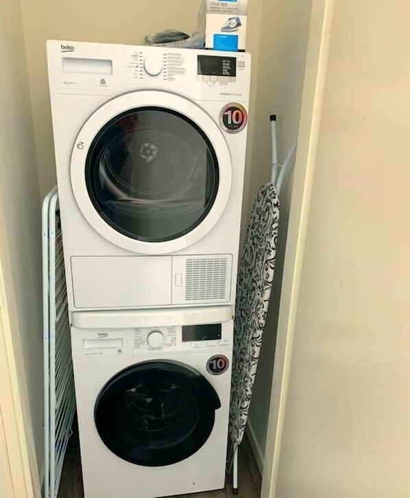 A stacked washer and dryer unit in a laundry room. - Stunning 45m2 Penthouse with Terrace (R-65-C) (Eindhoven)