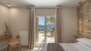 Un dormitorio con cama, una silla, un radiador, una ventana con cortinas y una pared de piedra con luces.