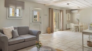 Una sala de estar con un sofá gris, una mesa de comedor con sillas y una zona de cocina con ventana.