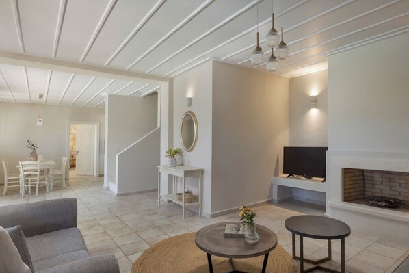 A modern living room with a fireplace, a sofa, a coffee table, and a television. - Fiscardo View Villas- Villa Yasemi (Fiskardo)
