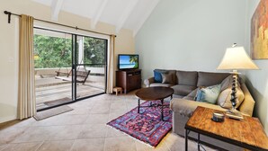 A living room with a sofa, a coffee table, a TV, and a large window with curtains. - Seascape Villa 35D*Quiet Villa*Beach Access*Pools* (Miramar Beach)