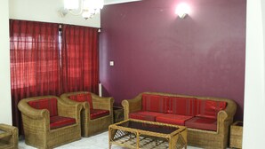 Un salon avec des meubles en osier, un canapé rouge et une table basse.