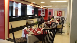 Un restaurant avec des tables dressées pour le service, un bar et un salon.