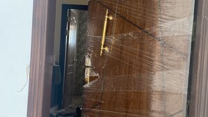 Uma porta de madeira parcialmente aberta, com sinais de danos e fita adesiva.