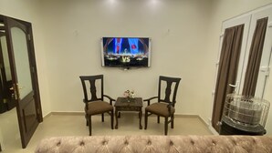 Uma sala de estar com um sofá estofado, duas poltronas, uma mesa de centro e uma TV de tela plana fixada na parede.