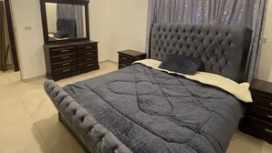 Quarto moderno com uma cama grande, penteadeira, espelho e luminária no teto.