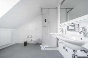 Deluxe vierpersoonskamer | Badkamer | Een douche, een haardroger, handdoeken, zeep