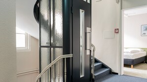 A staircase with a handrail leading to a bedroom with a bed and a nightstand. - Hotel Goldener Stern – Self check-in (Lucerne)
