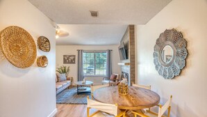 A dining area with a round wooden table and chairs, a fireplace, and decorative wall art.