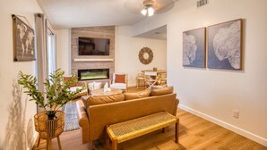 A modern living room with a sofa, a bench, a TV, and artwork on the walls.
