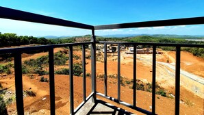 Un balcón con vistas a una obra en construcción y colinas al lejano.