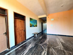 Un pasillo con una puerta de madera con la etiqueta 306, un banco y un cuadro de colores en la pared.
