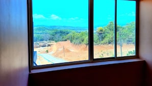 Una habitación con un ventanal que ofrece vistas a una zona en construcción y un área boscosa.