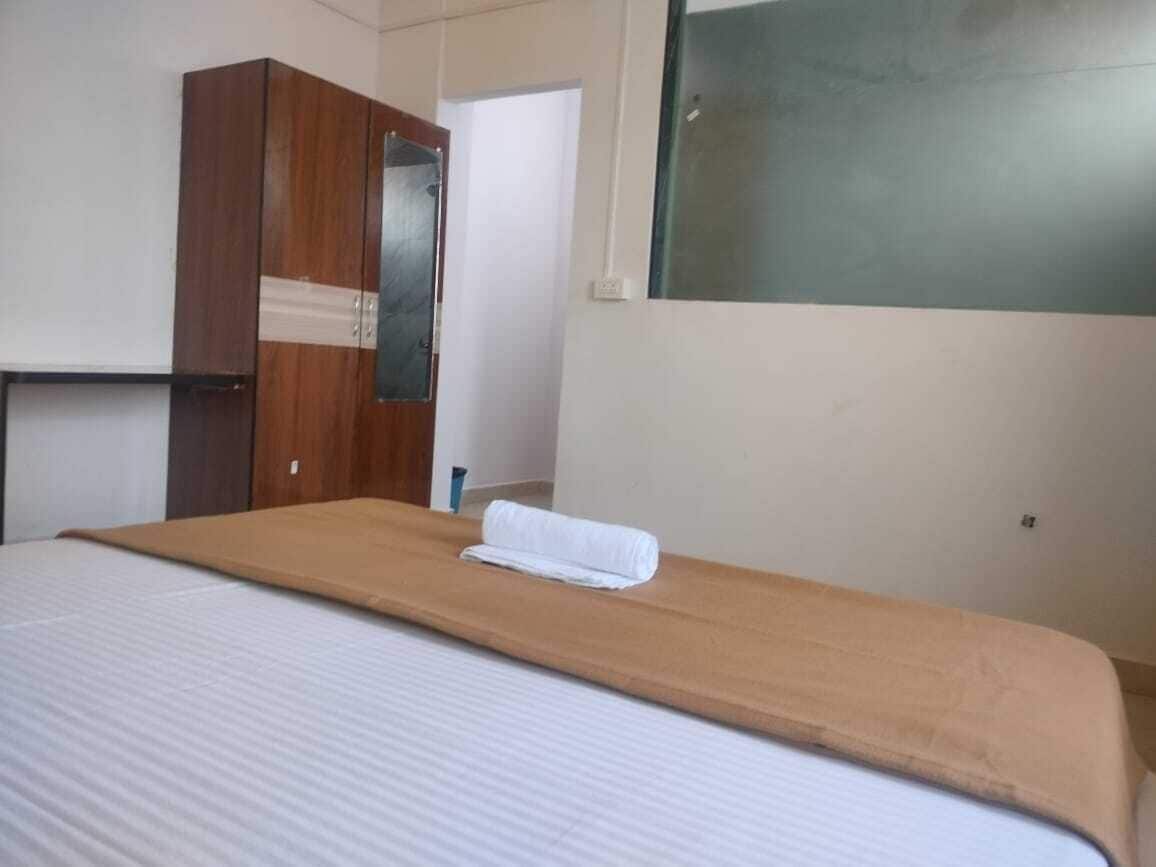 A hotel room with a bed, a wooden wardrobe, and a mirror.