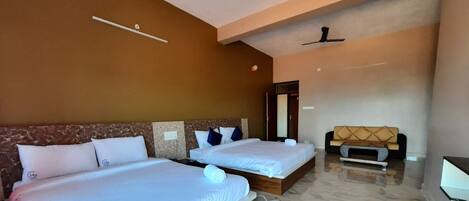 A hotel room with two beds, a sofa, a ceiling fan, and a marble floor.