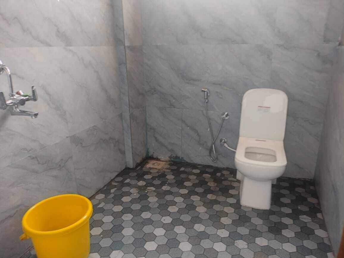 Un baño con inodoro, ducha y un cubo amarillo.