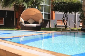 Una piscina con una silla de mimbre y un banco de madera.