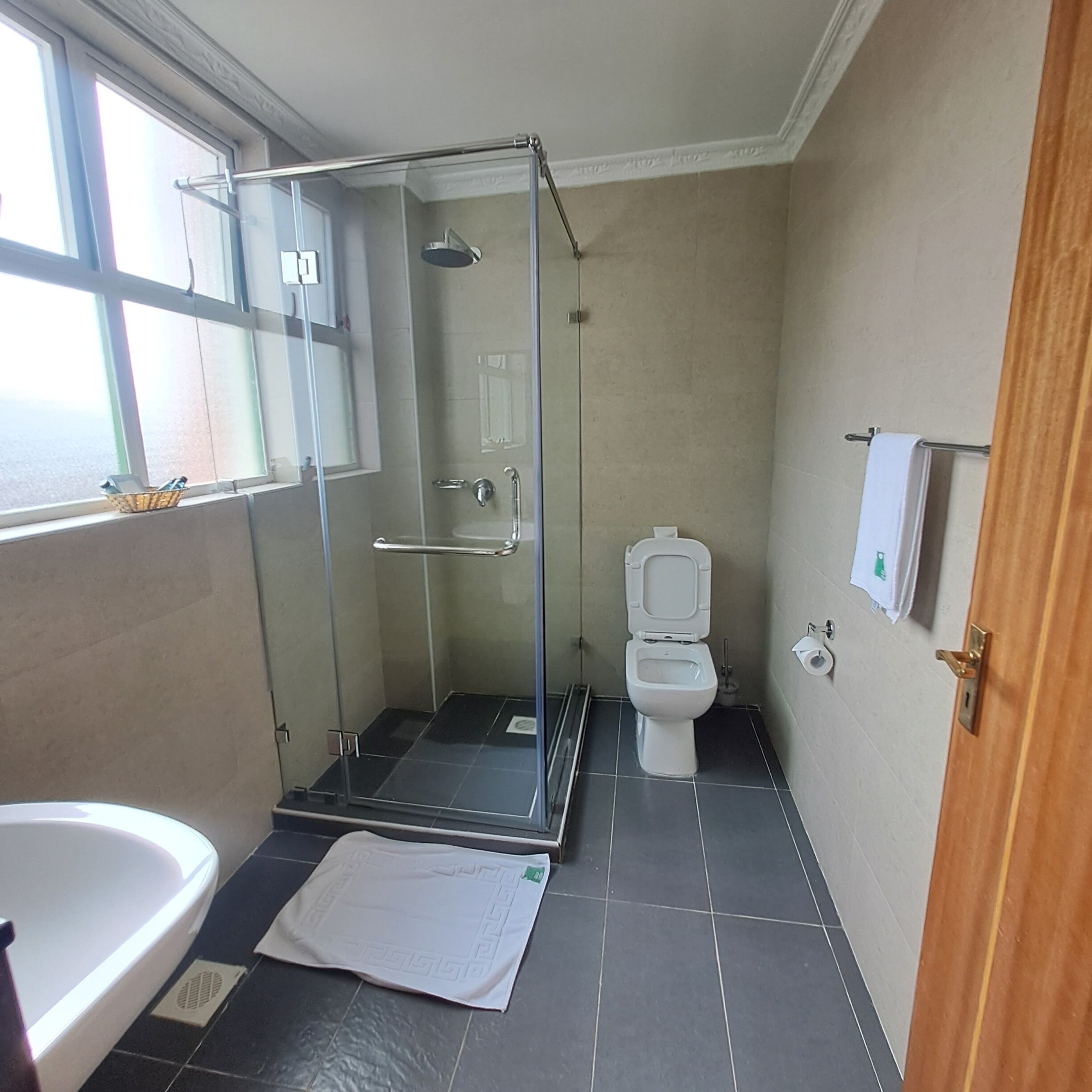 A bathroom with a glass-enclosed shower, a toilet, and a sink.