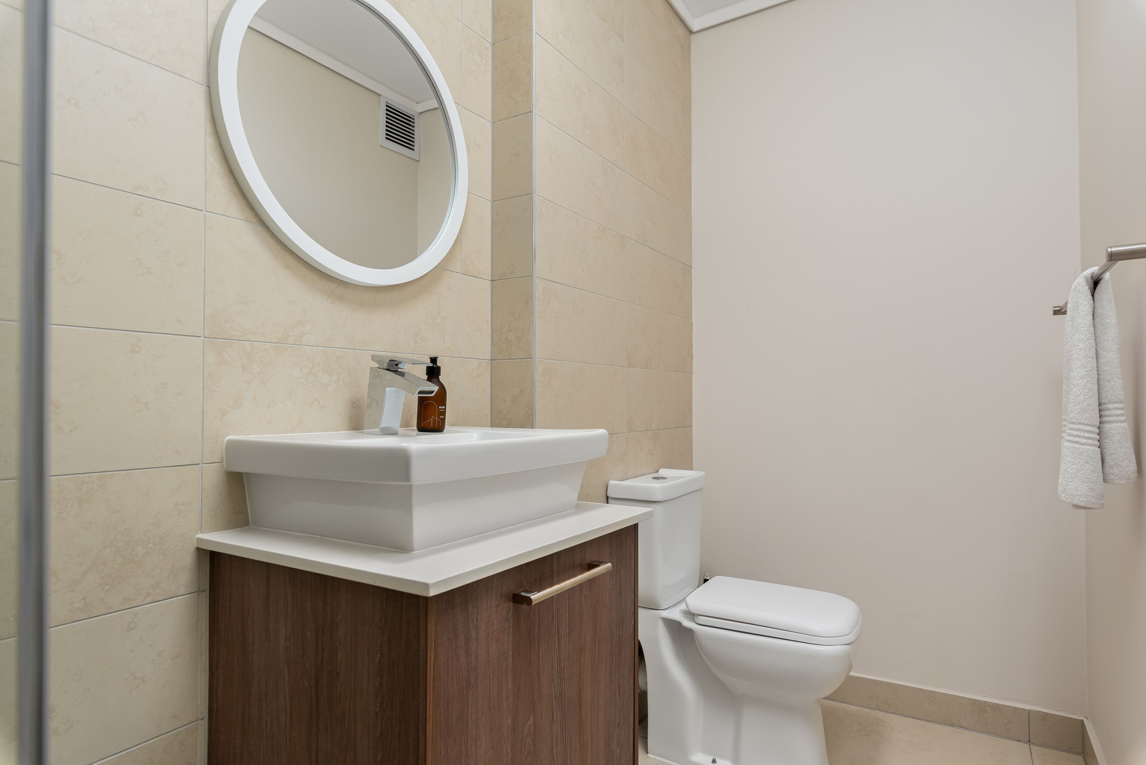 A bathroom with a white sink, a mirror, a toilet, and a towel rack.