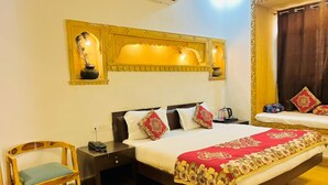 A hotel room with a bed, bedside table, chair, and decorative wall sconces. - Chirag Haveli - Near Golden Fort (Jaisalmer)