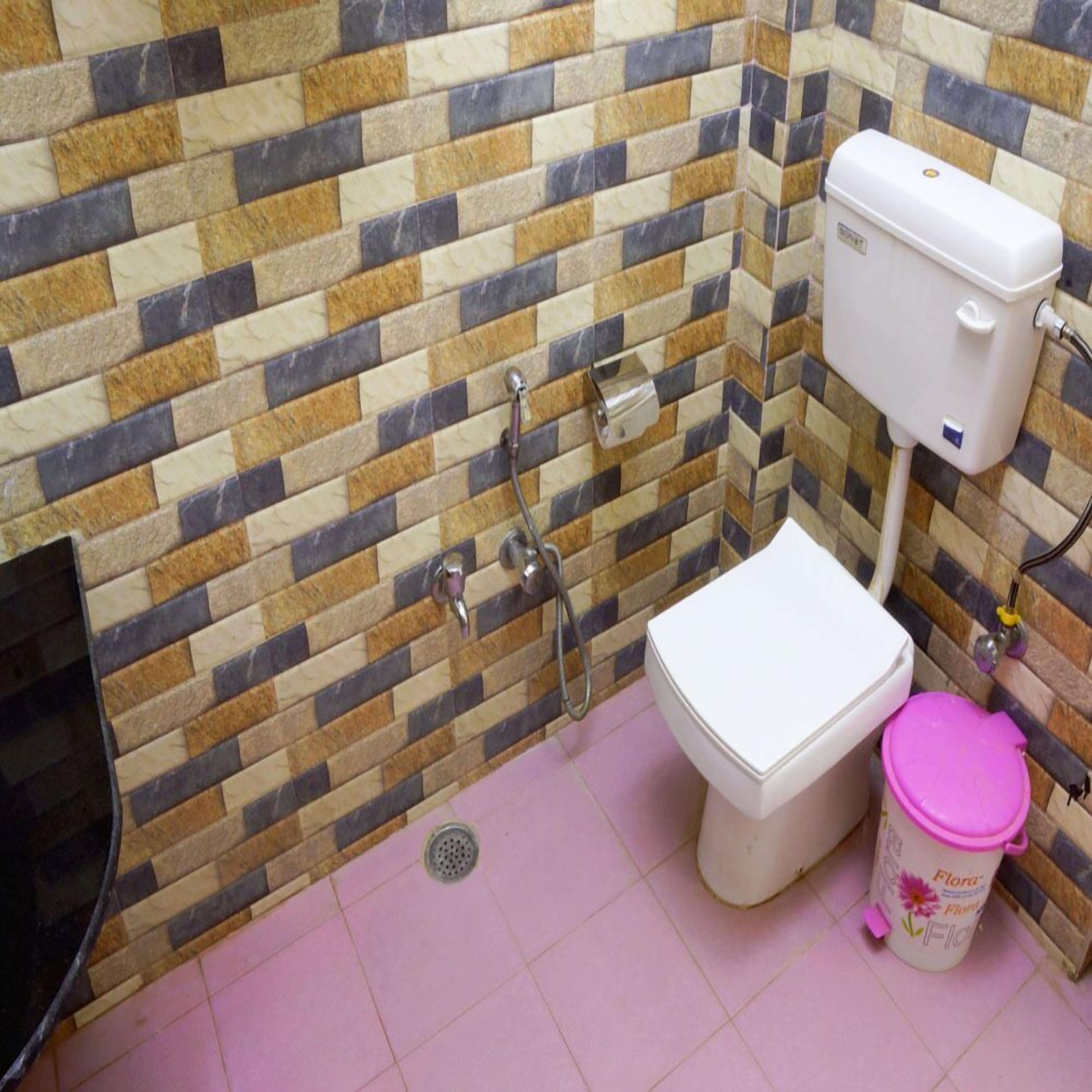A bathroom with a tiled wall, a toilet, a bidet, and a trash bin.