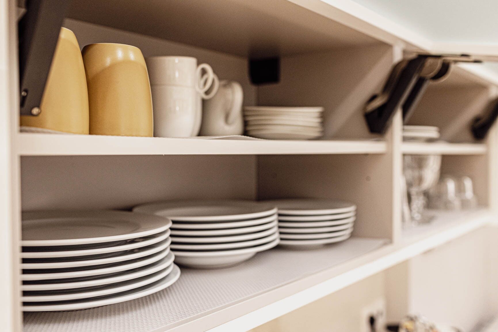 A kitchen shelf with stacked plates and cups.