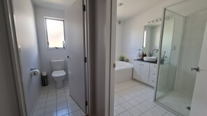 Un baño moderno con inodoro, lavamanos y ducha.