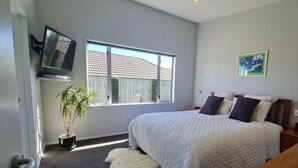 A bedroom with a large window, a bed with white bedding, a potted plant, and a painting on the wall. - Convenient town house close to town and a great location to explore the region (Richmond)