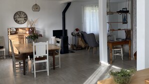 Un salón amplio con una mesa de comedor de madera, sillas blancas, una chimenea y una lámpara de techo moderna.