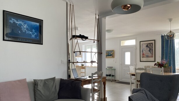 Una sala de estar moderna con un sofá gris, un sillón gris y un comedor con una mesa y sillas.