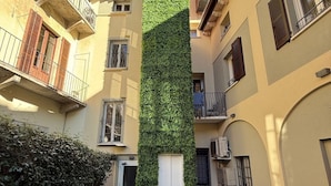 A courtyard with a vertical garden wall, a white door, and a small grassy area. - Malvezzi24 Boutique Rooms (Desenzano del Garda)