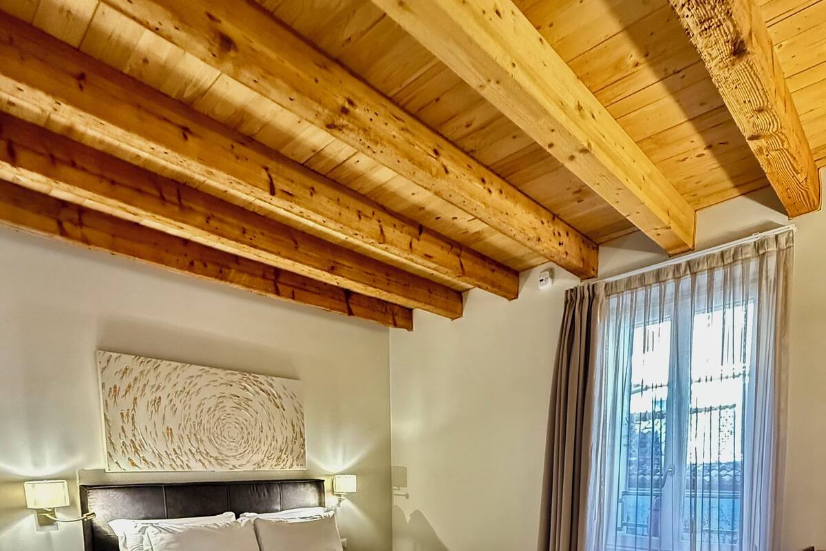 Une chambre à coucher avec un lit, une chaise, une table et une fenêtre avec des rideaux.