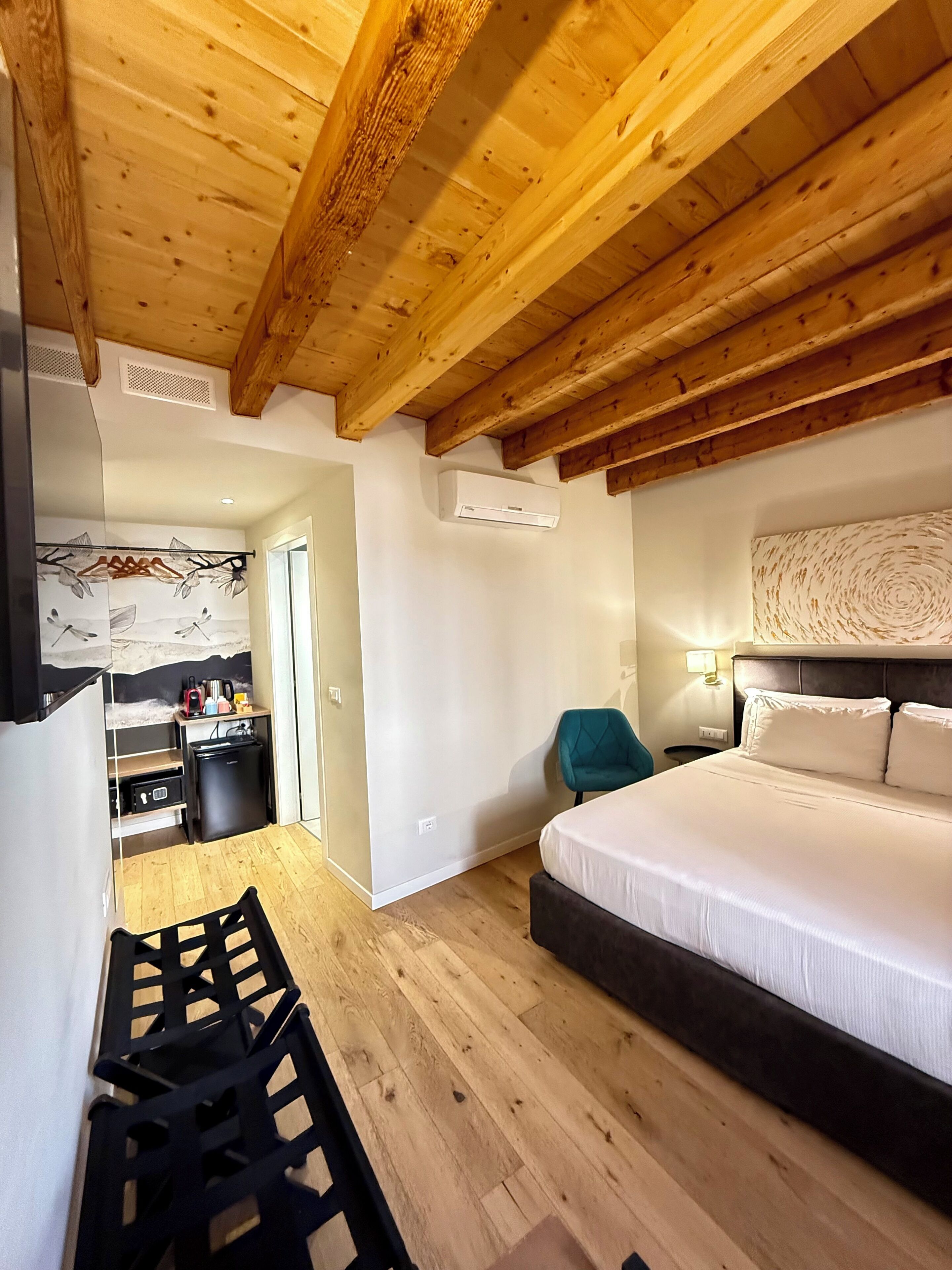 Ein Schlafzimmer mit Holzbalkendecke, einem Bett, einem Schreibtisch und einem Stuhl.