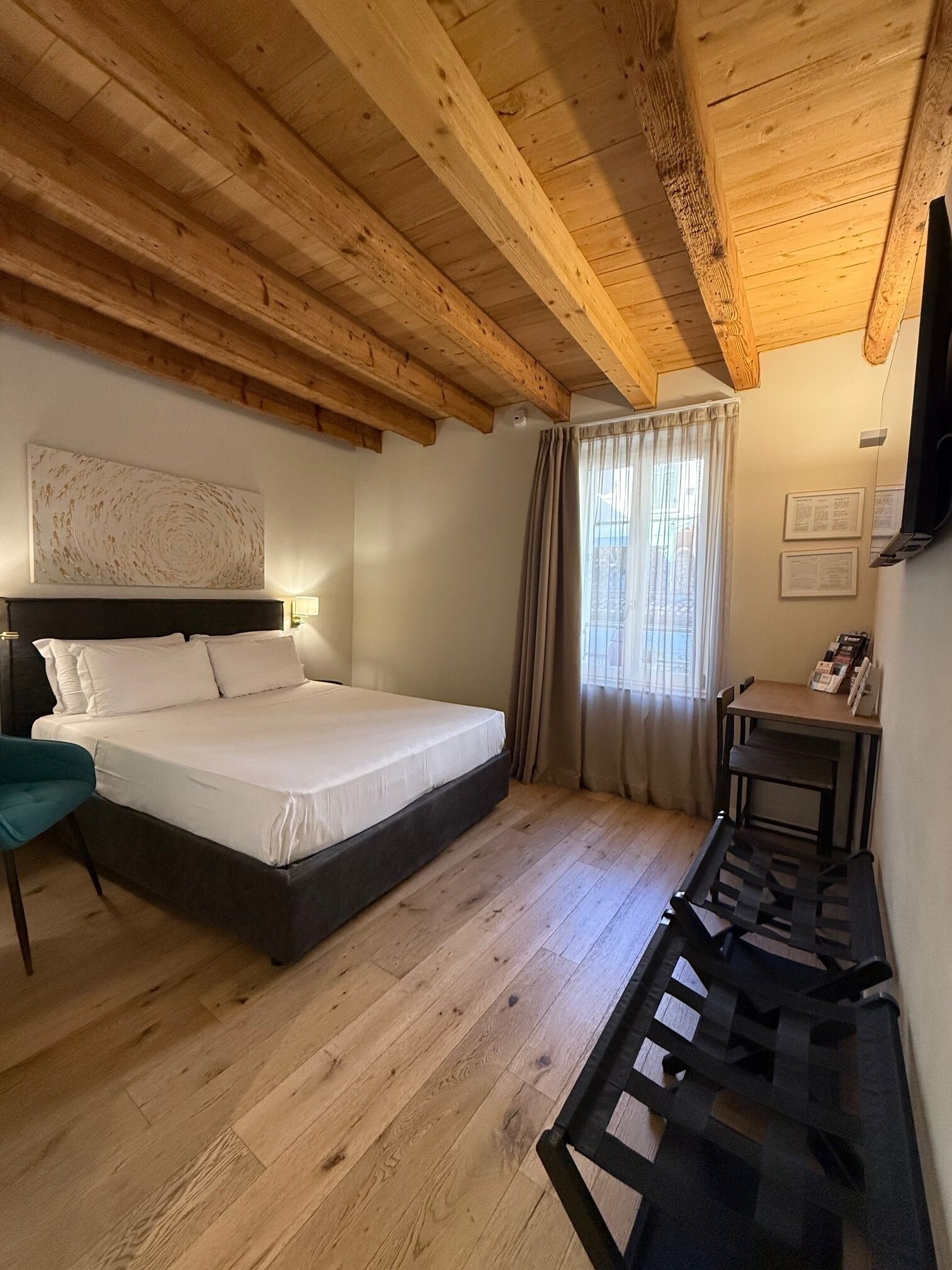 Un dormitorio con techo de madera, cama, escritorio y silla.