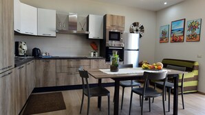 A modern kitchen with wooden cabinets, a built-in oven, and a dining area with a table and chairs. - Villa with pool for 8 guests with 3 bedrooms (Puglia)