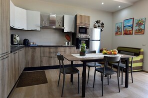 Une cuisine moderne avec des meubles en bois, un four encastré et un coin repas comprenant une table et des chaises.