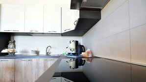 A modern kitchen with white cabinets, a black countertop, and a stainless steel range hood. - Villa with pool for 8 guests with 3 bedrooms (Puglia)