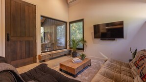 Ein modernes Wohnzimmer mit einer großen Holztür, einem an der Wand montierten Fernseher und einer gemütlichen Sitzecke mit Sofa und Couchtisch.