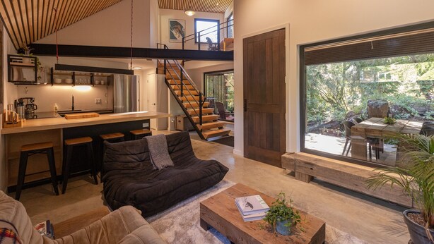 Ein moderner Lofts-Wohnraum mit Küche, Essbereich und einem großen Schiebeglastür zu einem Garten.