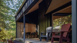 Eine moderne Terrassenanlage im Freien mit Grill aus Metall, Holzgeländern und zwei Adirondack-Stühlen.
