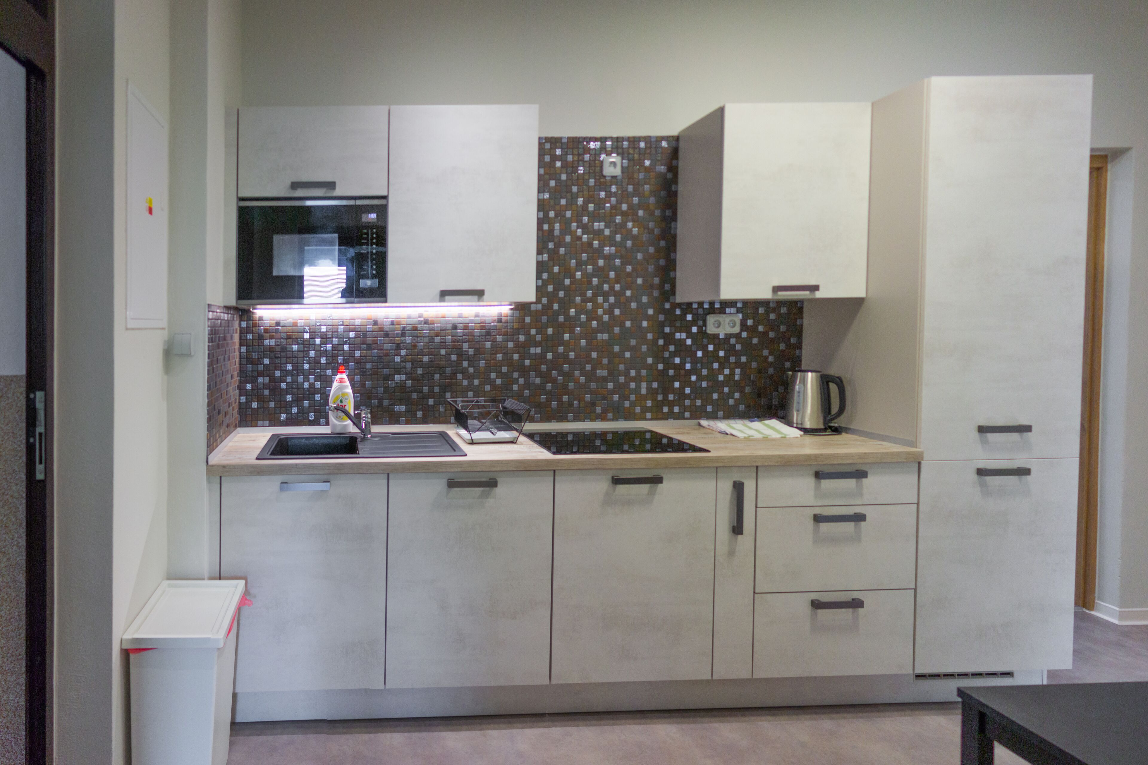 Una cocina moderna con un lavamanos de acero inoxidable, un microondas y un salpicadero de azulejos.